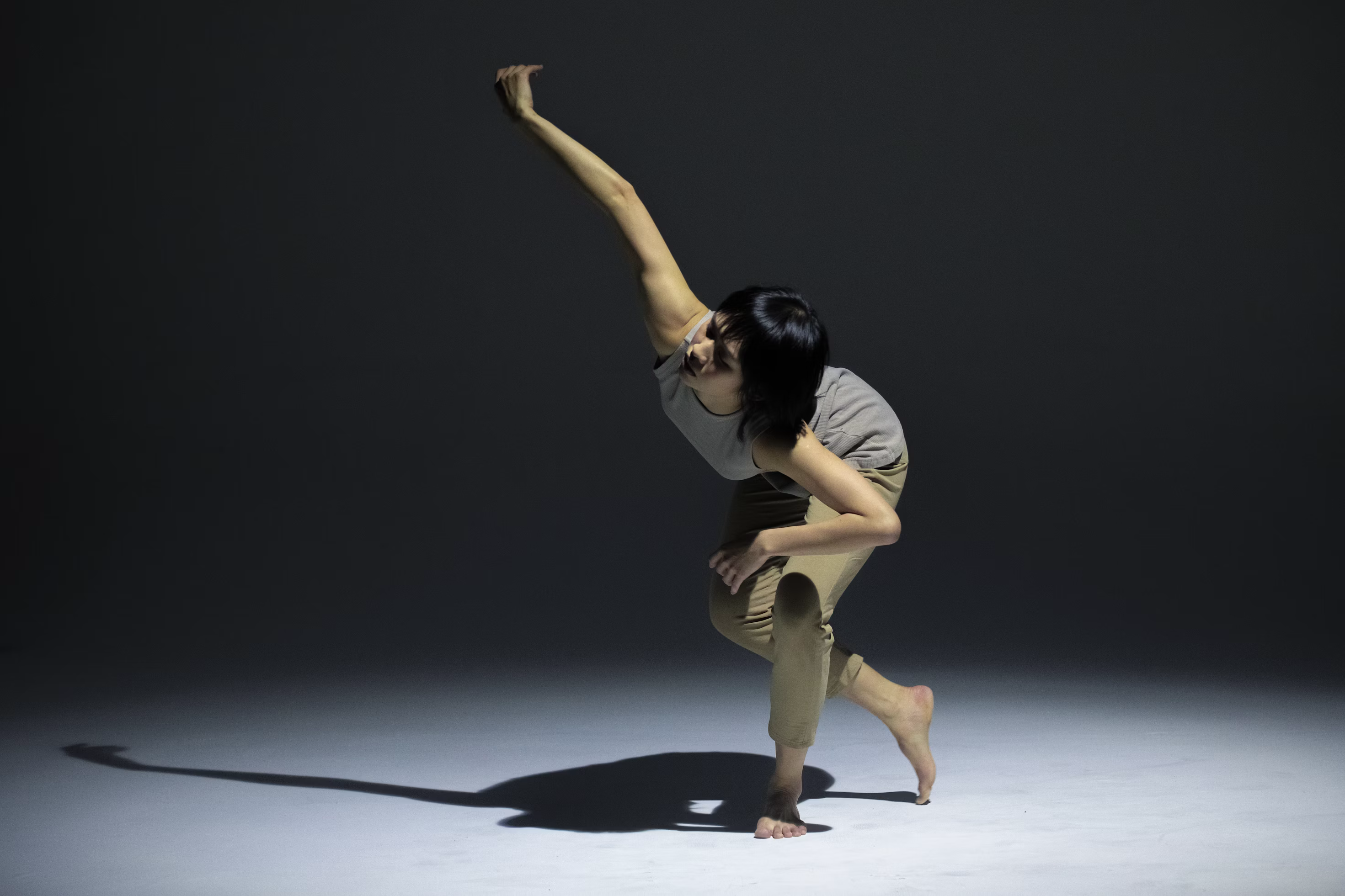 Photo of a female dancer in a modern dance pose with a spotlight on her.